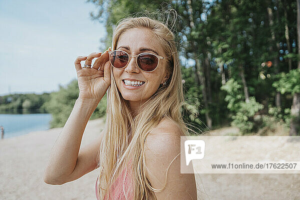 Smiling woman wearing sunglasses at lakeshore