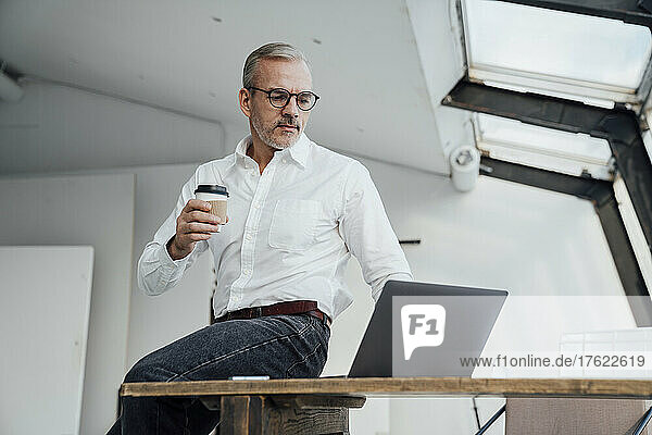 Architect using laptop sitting on desk in office