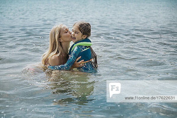 Mother kissing daughter in lake on weekend