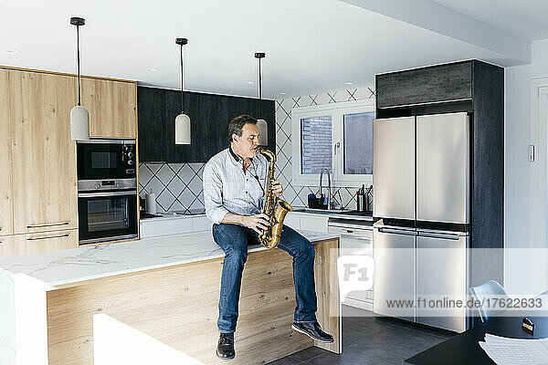 Musician playing saxophone sitting on kitchen island at home