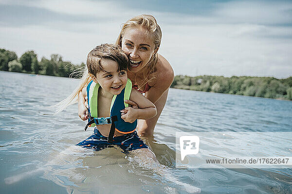 Glückliche Mutter spielt mit Sohn im See