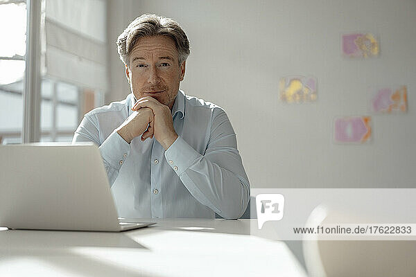 Businessman with hand on chin sitting at desk