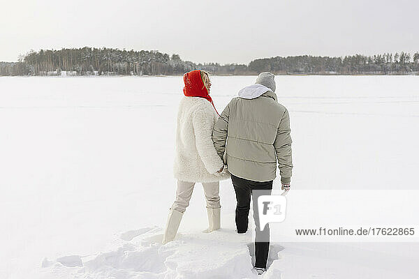Couple holding hands walking on snow in winter