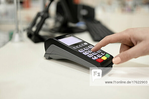 Hand mit Kreditkartenleser an der Kasse im Geschäft