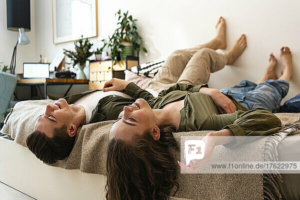 Smiling young couple lying on bed at home