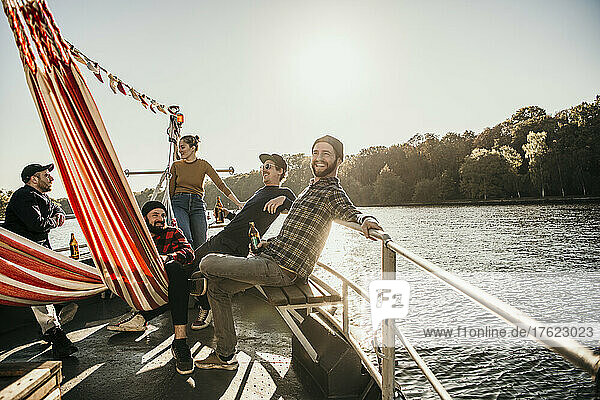 Smiling friends spending leisure time together sitting on boat bow