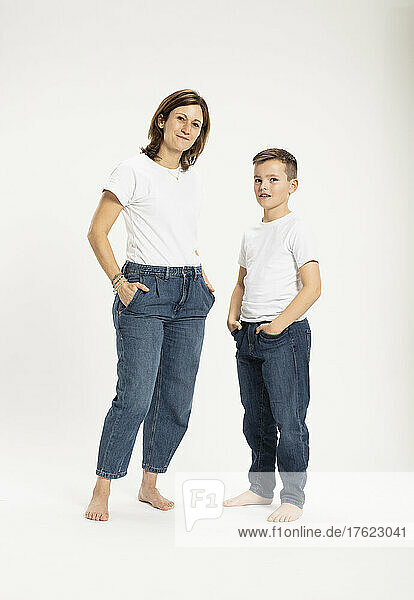 Mother with son standing with hands in pockets at studio