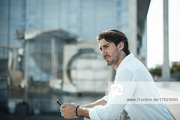 Smiling businessman with smart phone on sunny day