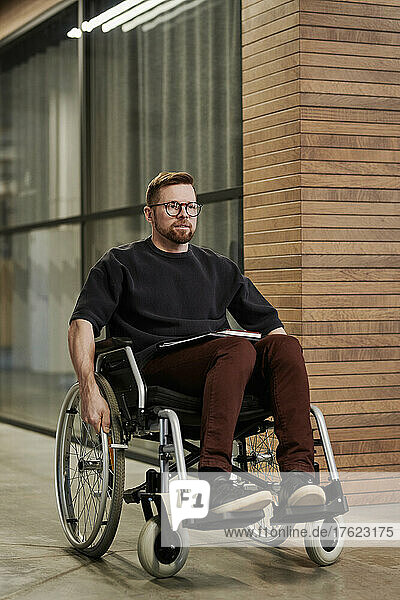 Businessman sitting on wheelchair in office corridor