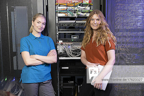 Smiling IT technicians standing in server room