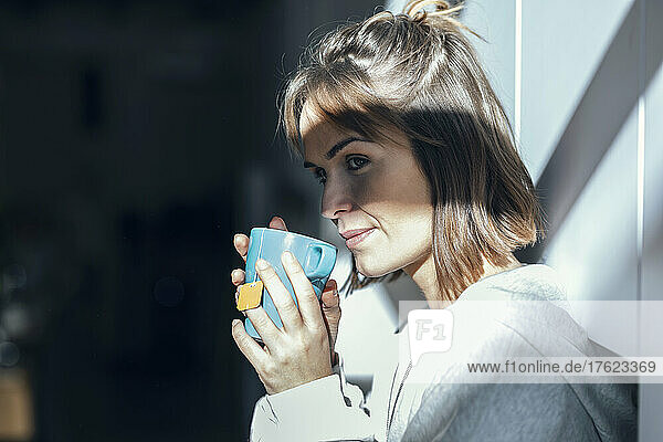 Woman having tea by wall