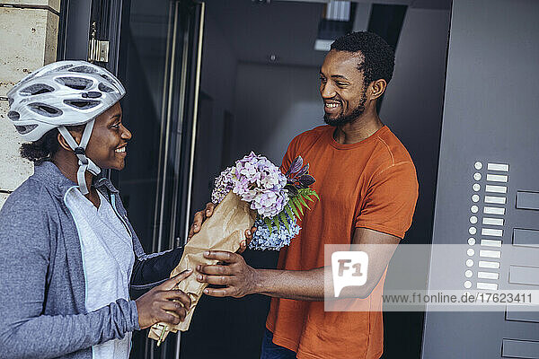 Delivery woman giving flower bouquet at doorway