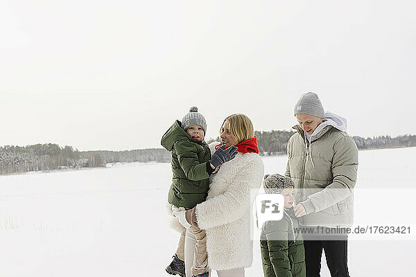 Mann und Frau mit Söhnen stehen im Winter auf Schnee
