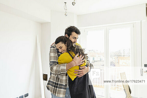 Junges Paar umarmt sich im neuen Zuhause