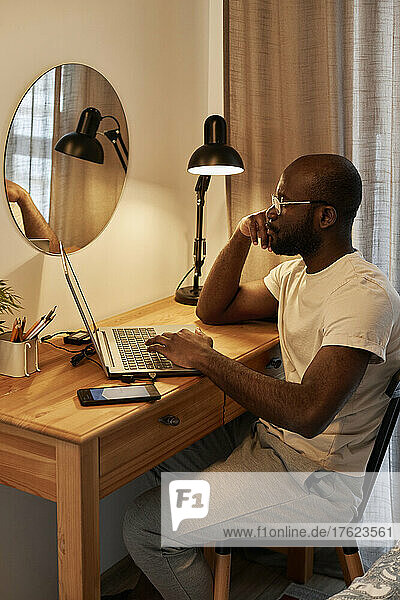 Thoughtful freelancer working on laptop at home office