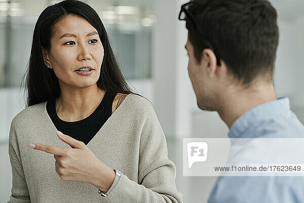 Businesswoman making hand gesture talking to colleague at office