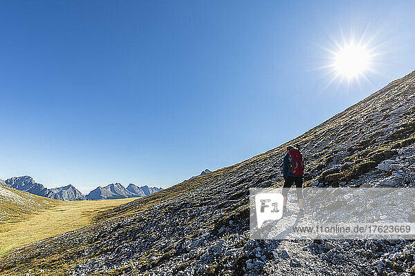 Sun shining over female hiker admiring surrounding landscape on way to Brunnensteinspitze