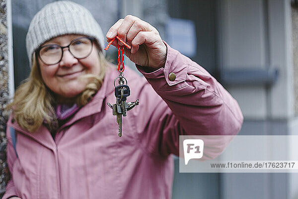Senior woman in warm clothing showing keys