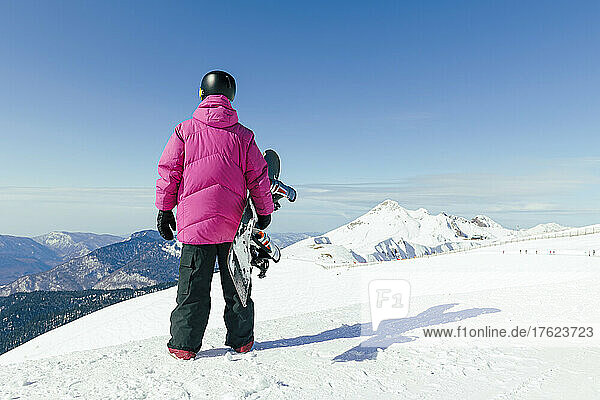 Man with snowboard standing on snowy mountain