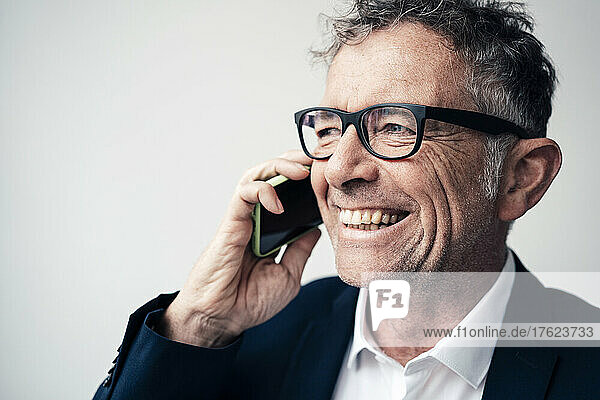 Cheerful businessman talking on smart phone at studio