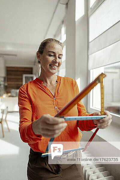 Lächelnde Geschäftsfrau macht Hausform mit Lineal im Büro