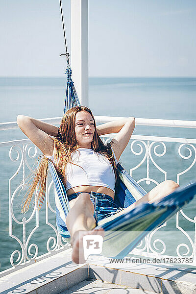 Smiling young woman resting on hammock