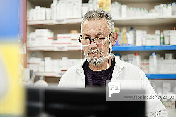 Pharmacist wearing eyeglasses using computer in pharmacy