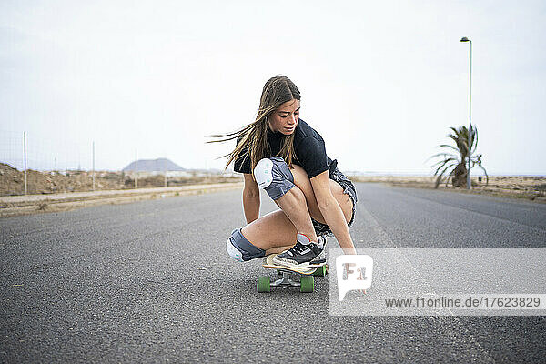 Young woman skateboarding on road