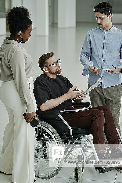 Disabled businessman discussing with colleague in modern office