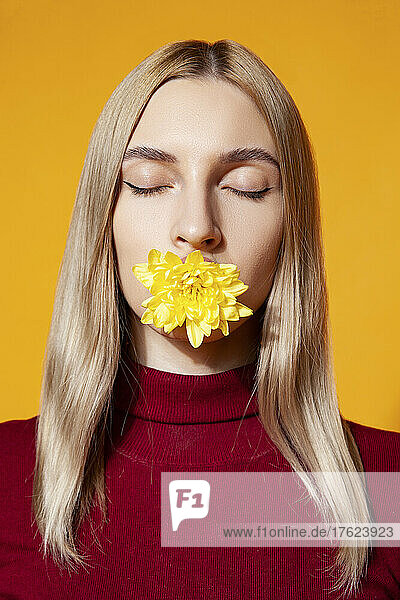 Woman holding flower in mouth at studio