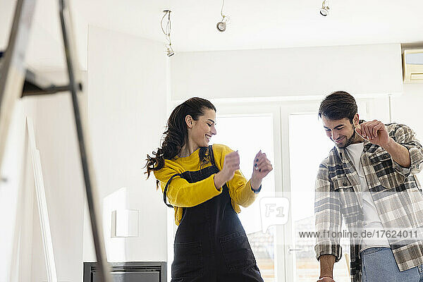 Happy young couple dancing in living room