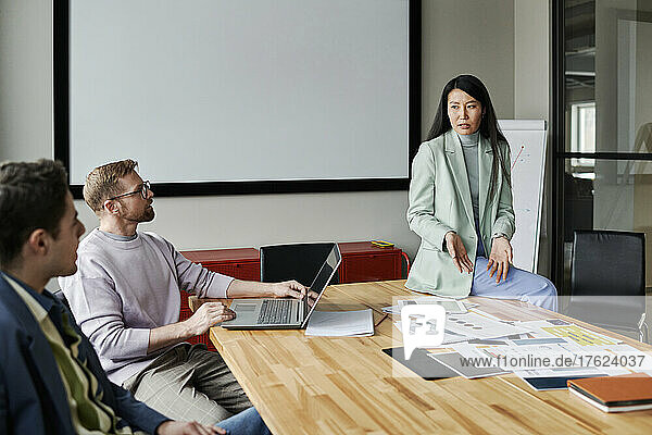 Businesswoman discussing with colleagues in meeting room at office