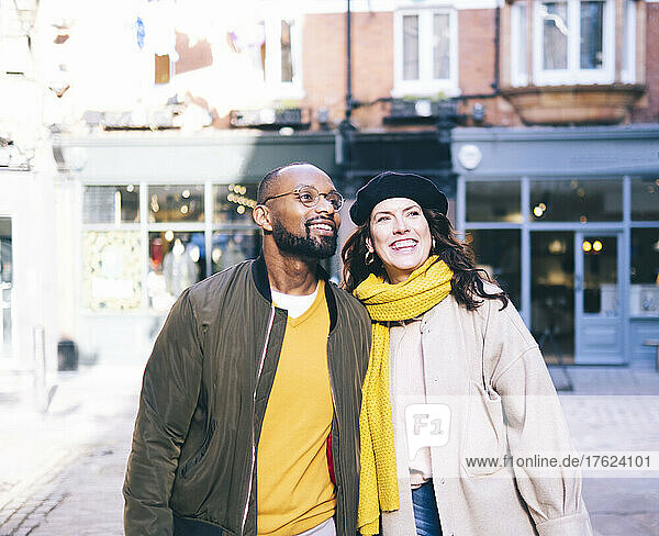 Smiling couple with warm clothing day dreaming on footpath