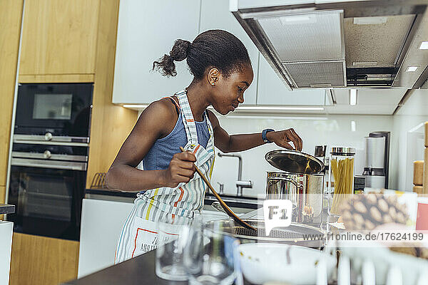 Pre-adolescent girl cooking food in kitchen
