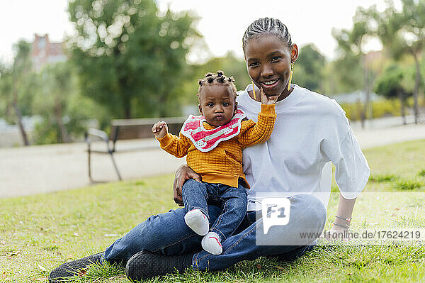 Smiling woman with daughter sitting at park