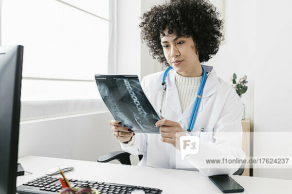 Doctor examining X-ray report sitting at medical clinic