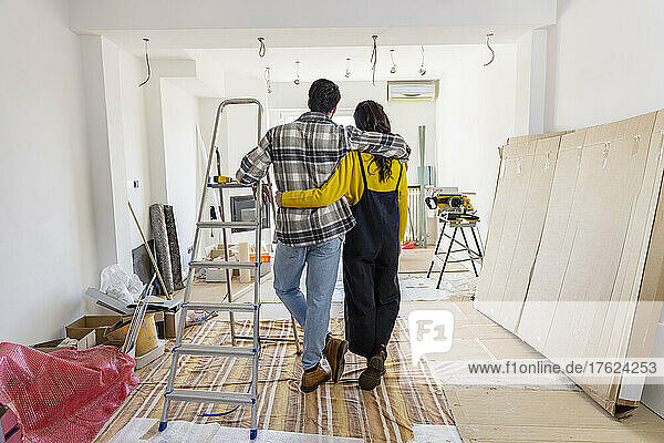 Young couple with arms around looking at new home