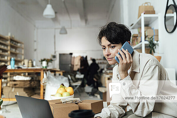 Owner talking on phone and working at ceramics workshop