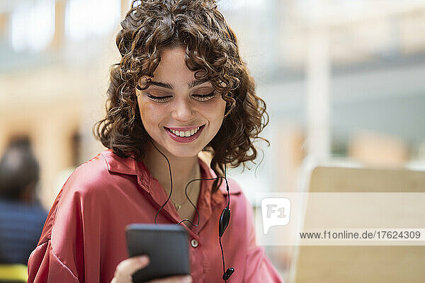 Smiling freelancer using smart phone in cafe