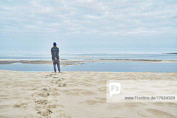 Tourist blickt auf das Meer und steht auf einer Sanddüne