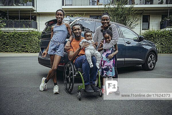 Father sitting on wheelchair by family on road