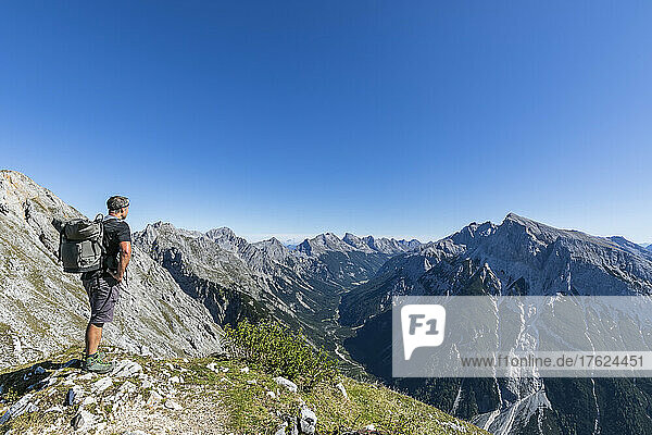 Male hiker admiring view of Mittenwalder Hohenweg in summer