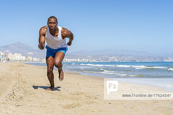 Sportsman running at beach on sunny day
