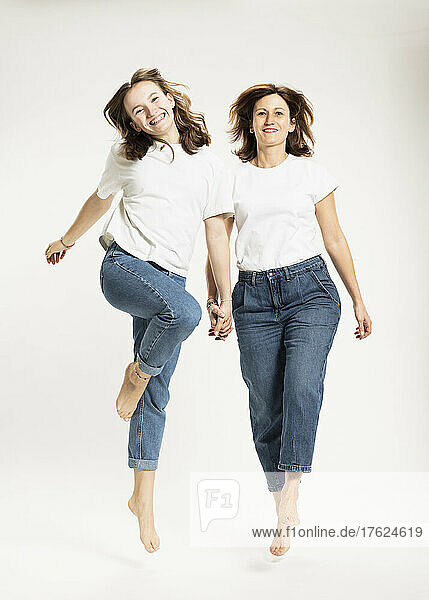 Playful mother and daughter jumping in studio