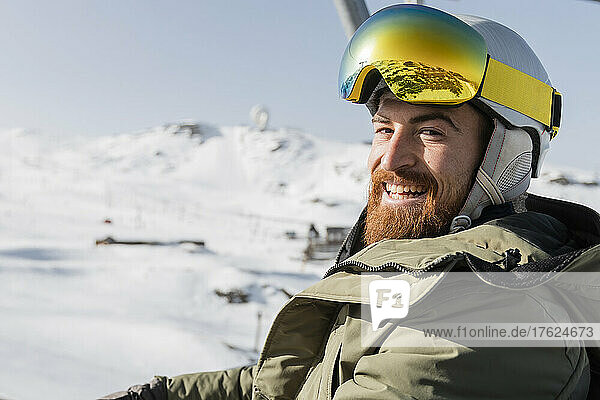 Smiling man wearing ski helmet and goggles on sunny day
