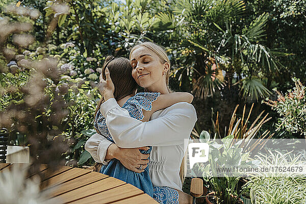 Lächelnde Mutter umarmt Tochter im Hinterhof