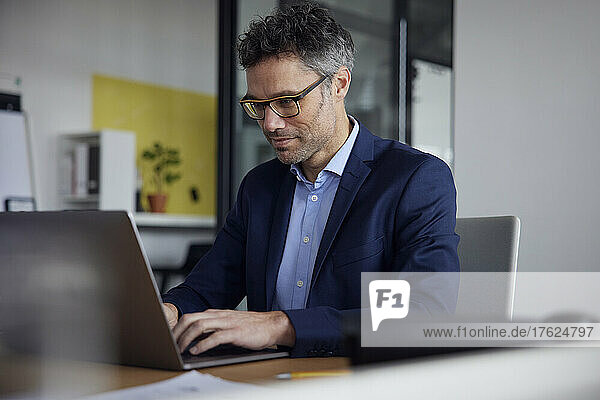 Geschäftsmann mit Brille und Laptop am Arbeitsplatz