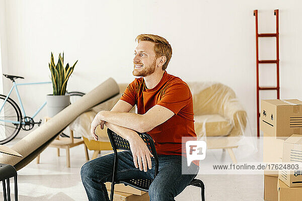 Smiling man sitting on chair in living room at home