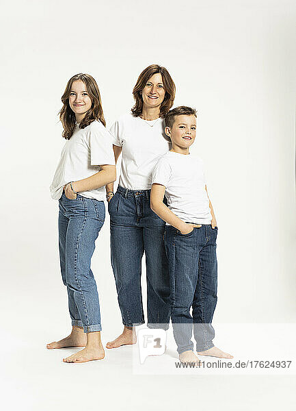 Mother with daughter and son standing with hands in pockets