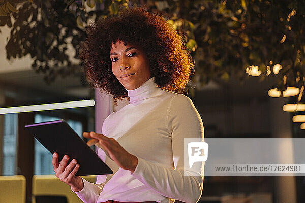 Businesswoman with tablet computer in illuminated office